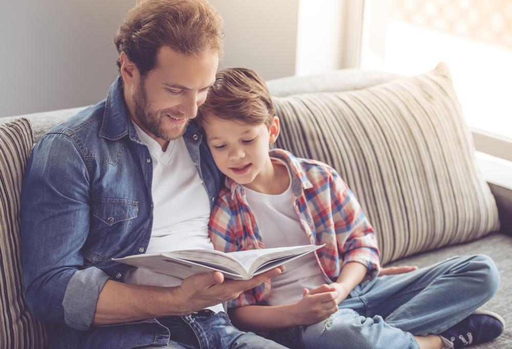 father and son reading on sofa