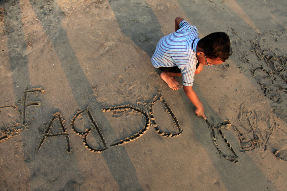 a boy is writing on the beach