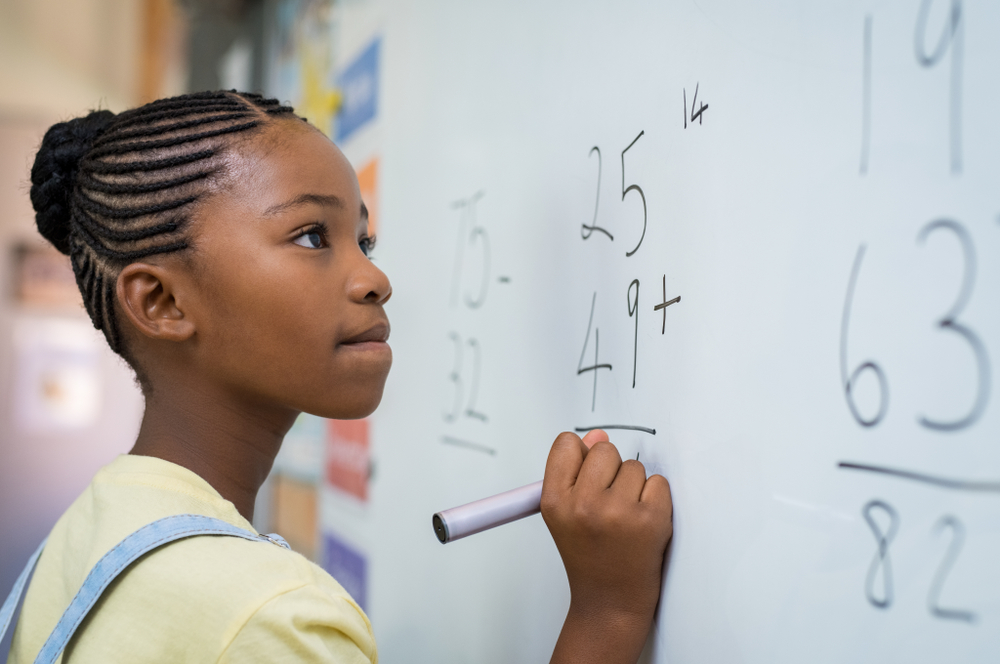 girl at math class writing on board