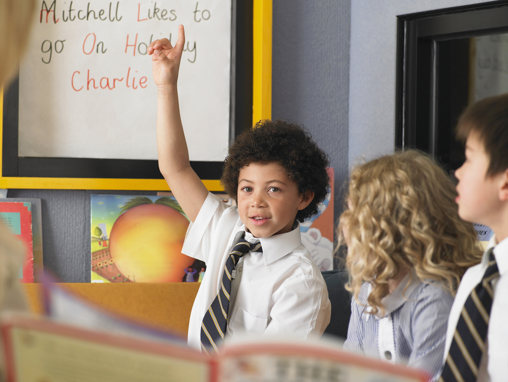 a boy in the classroom raising his hand