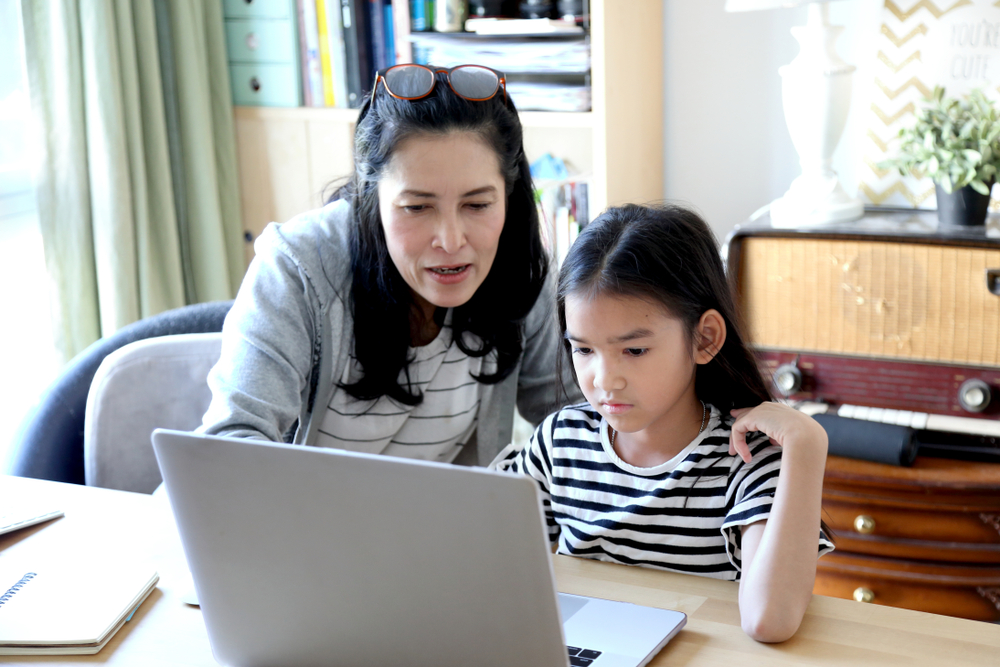 a teacher and a girl in front of a laptop