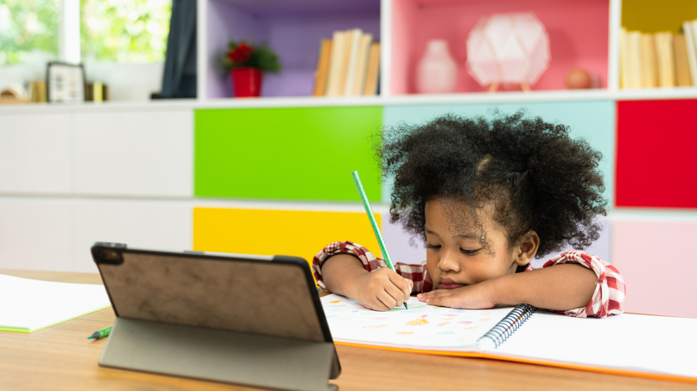 a girl is writing on front of a ipad