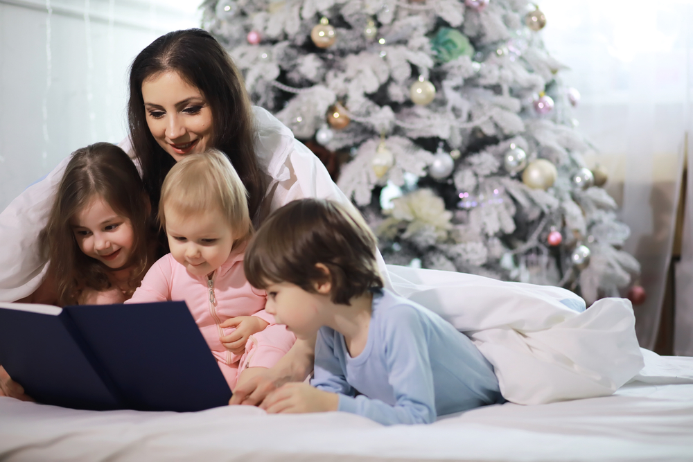 mom with kids reading a book during christmas