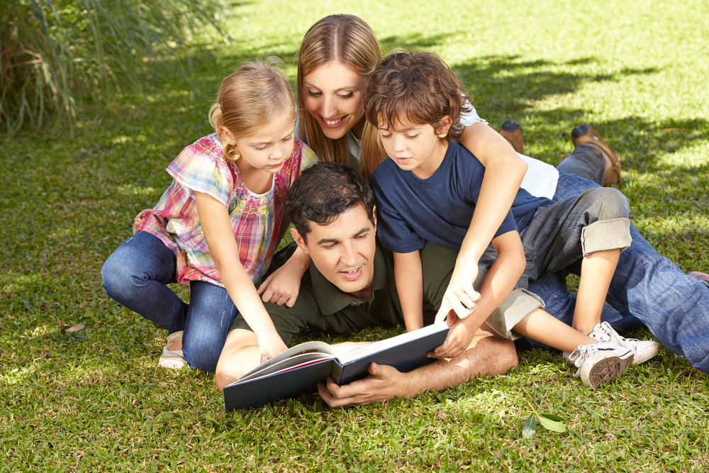 Family reading outdoors.