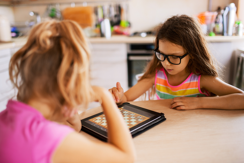 girls playing chess on ipad