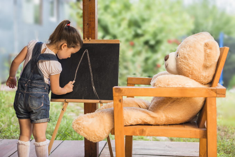 Child teaching teddy.