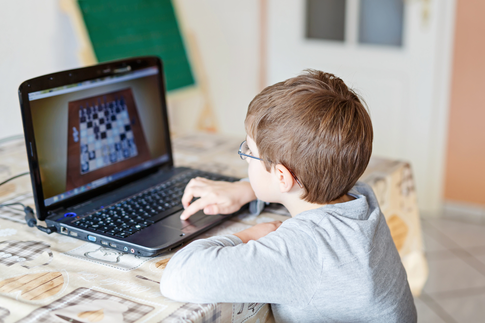 Teenage boy learning to play chess online with tablet computer