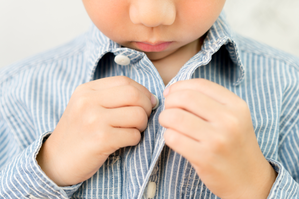 boy is buttoning up the shirt